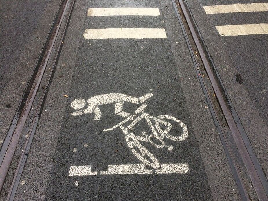 Beispielfoto eines Fahrradpiktogramms auf der Fahrbahn zwischen den Gleisen, welches unmittelbar vor Ort auf die erhöhte Sturzgefahr hinweisen soll.