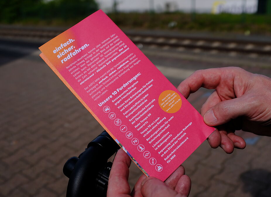 2026-04-17_Dormagen_Verkehrssicherheit__ADFC_NRW Eine Person hält einen Flyer in den Händen.